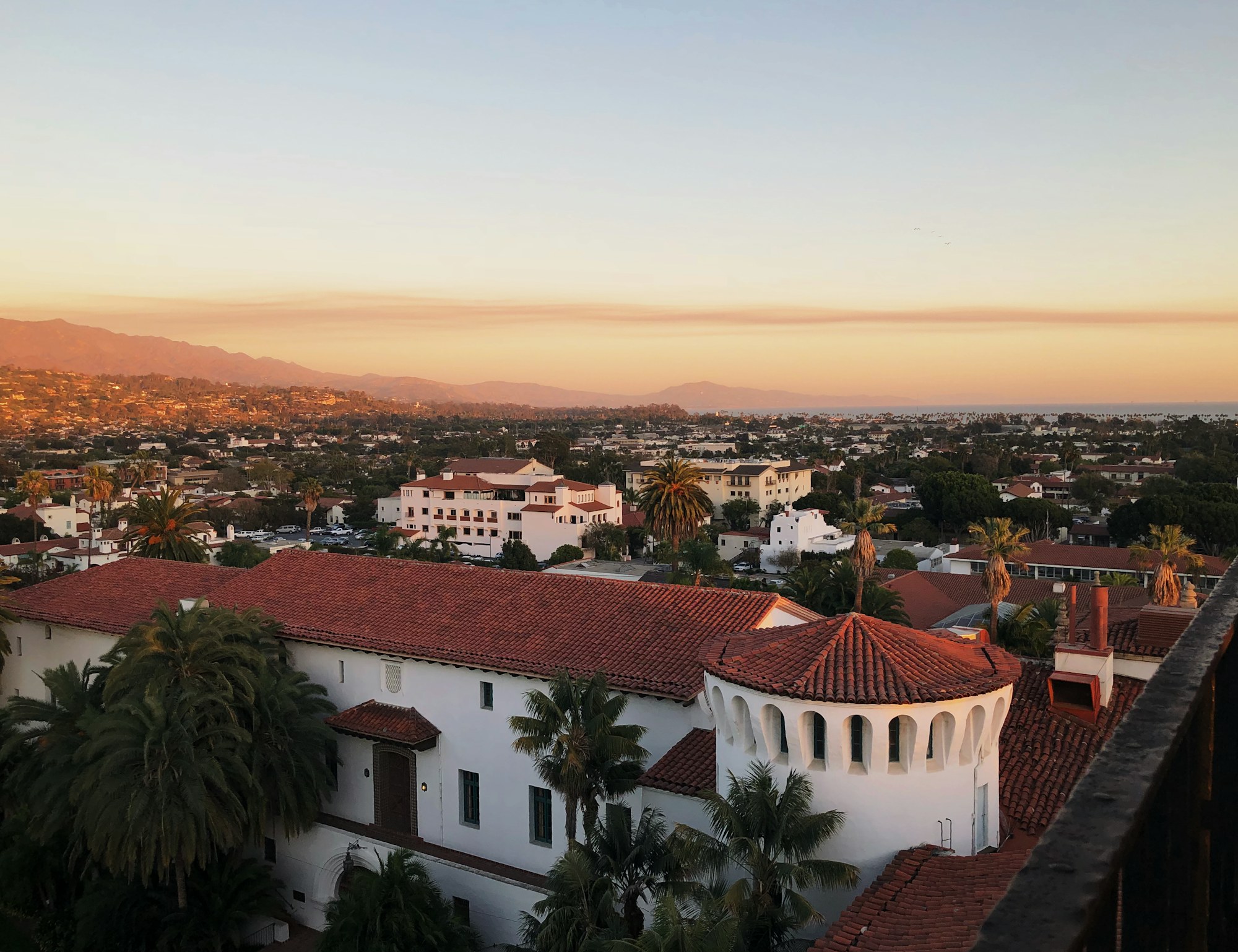 Santa Barbara rooftops, palms, and mountains in warm evening light